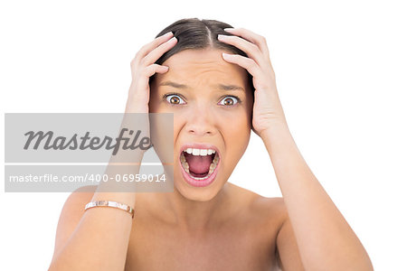 Screaming woman holding hands on head against white background