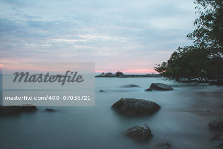 View sunset on the rocky beach when high tide with cloudy sky