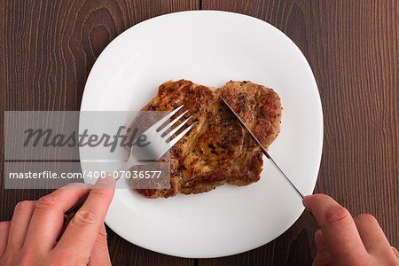Someone eating delicious grilled steak on a white plate