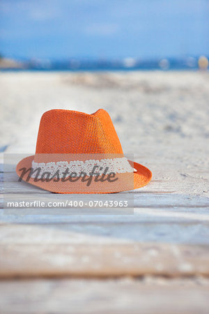 Orange straw hat on the beach with sea background
