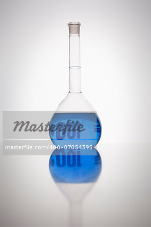 A glass bottle with blue liquid in a laboratory