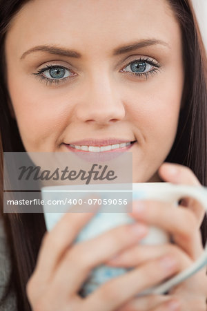 Smiling brunette holding a cup of coffee and looking at camera