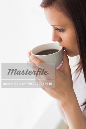 Thoughtful teen holding a cup of coffee and looking away on white background