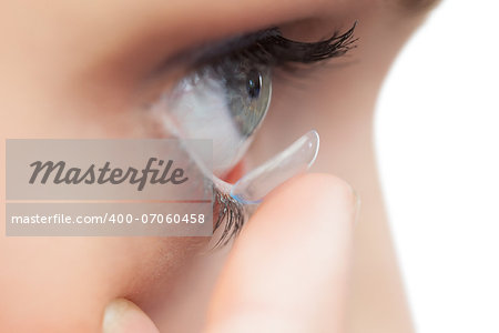 Extreme close up on young model applying contact lens on her blue eyes