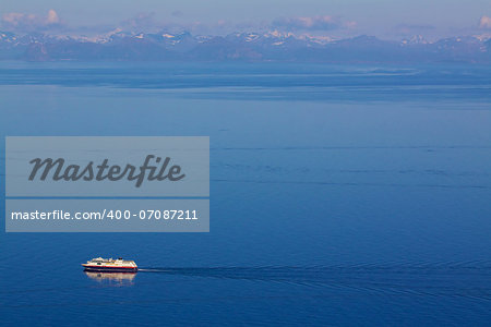 Aerial view of traditional norwegian cruise ship with mountainous norwegian coastline in the background