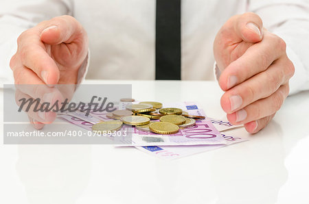 Male hands around Euro banknotes and coins as if they are giving power and energy to money.
