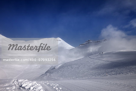 Ski slope with snowmobile trail in nice day. Georgia, ski resort Gudauri. Caucasus Mountains. Wide-angle view.