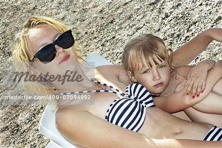 Different years two Caucasian sister girls resting on the beach
