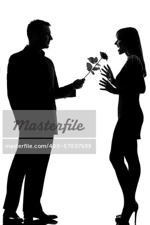 one caucasian lovers couple man offering rose flower and woman surprised in studio silhouette isolated on white background