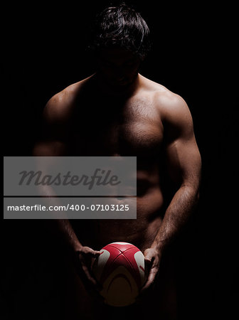 one caucasian sexy naked  man portrait holding rugby ball on studio black background