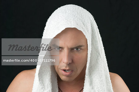 Close-up of a intense man thinking, workout towel over head, looking down.