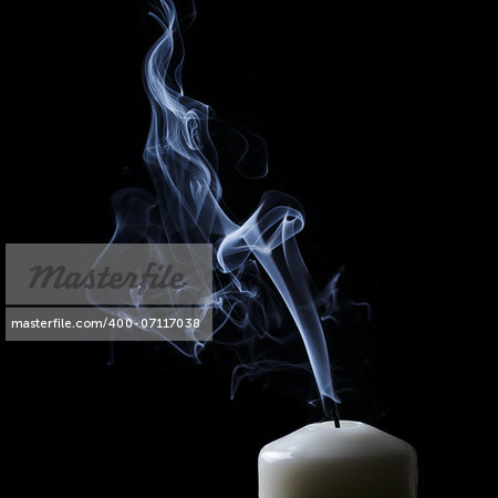 extinguished candle with blue smoke, black background