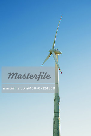 A wind engine in front of a blue summer sky. Vertical