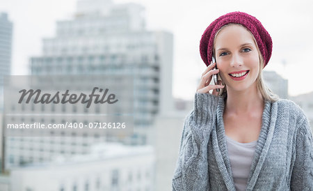 Cheerful pretty blonde on the phone outdoors on urban background