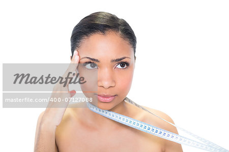 Thinking young dark haired model holding measuring tape on white background