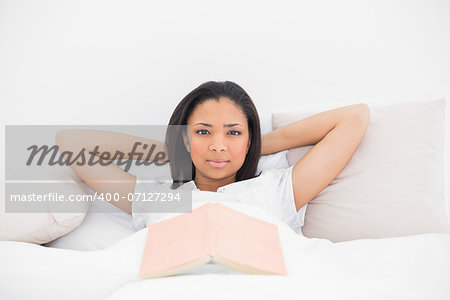 Attractive young dark haired model relaxing in her bed in bright bedroom