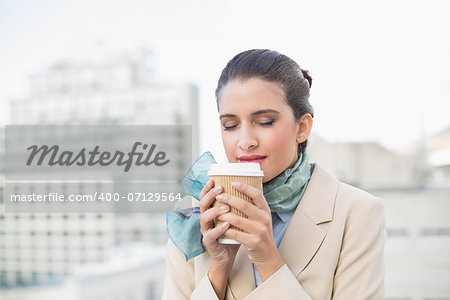 Peaceful smart brown haired businesswoman enjoying coffee outdoors