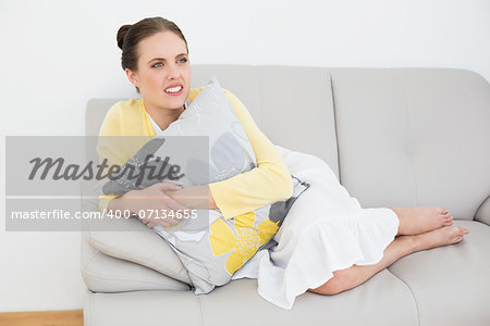 Thoughtful young woman relaxing on sofa at home as she looks away