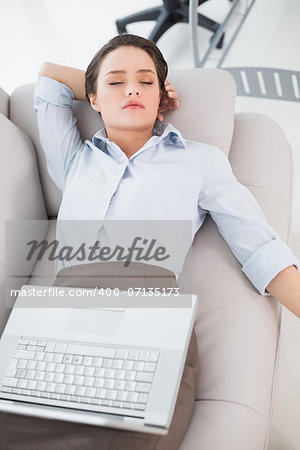 High angle view of a young woman with laptop lying on sofa at home