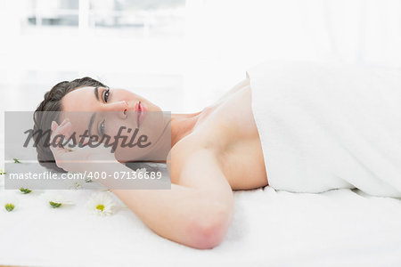 Portrait of a beautiful young woman with flowers lying in beauty salon