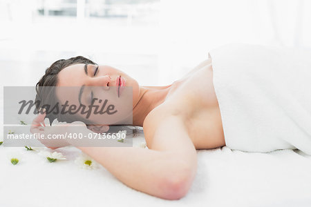 Beautiful young woman with flowers lying in beauty salon