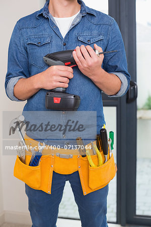 Close up mid section of a handyman with drill and toolbelt