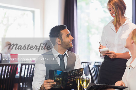 Handsome businessman ordering food from waitress in a restaurant
