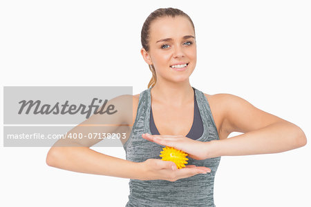 Happy woman holding yellow massage ball between her hands smiling at camera