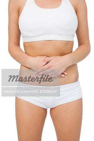 Mid section of young woman touching her belly with her hands on white screen