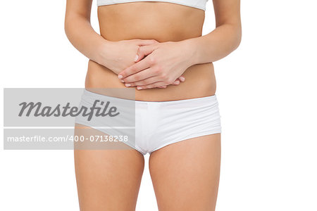 Mid section of woman touching her belly with her hands on white background