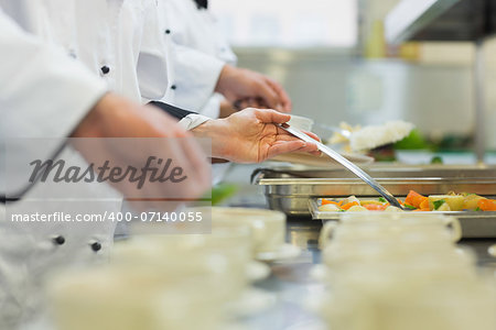 Chefs standing in a row preparing food in a modern kitchen