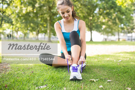 Active content brunette tying her shoelaces in a park on a sunny day