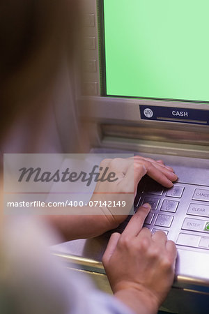 Woman entering pin and covering keyboard at an ATM