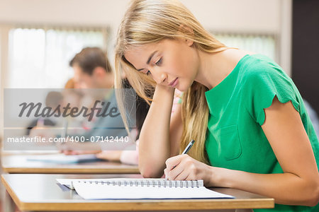 Side view of a group of young students writing notes in the classroom