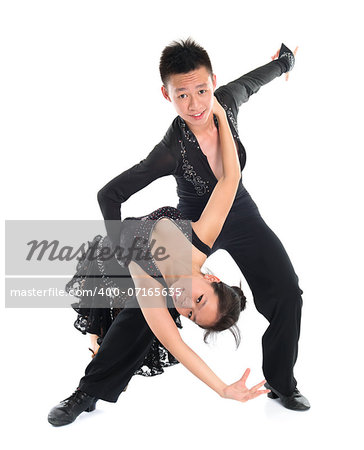 Modern young Asian teens couple latin dancers dancing in front of the studio background, full length isolated white.