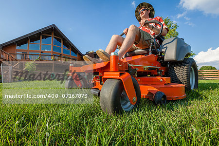 A man is mowing backyard on a riding zero turn lawnmower