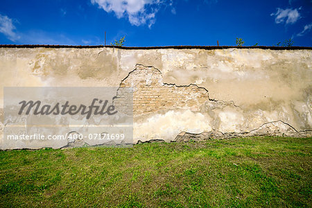 Old brick wall with lots of copy space also showing grass and sky