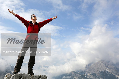 Young mountaineer standing on a rock and enjoying freedom in the mountains