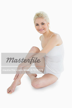 Full length portrait of a toned blond sitting over white background