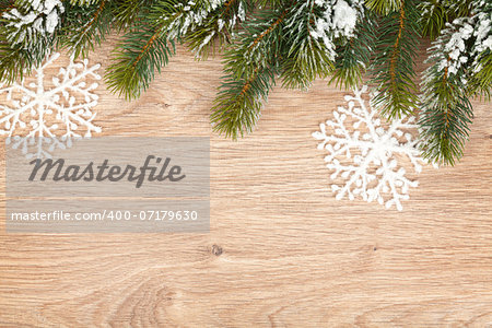 Christmas fir tree covered with snow on wooden board background