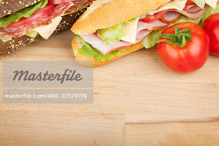 Fresh sandwiches with meat and vegetables and tomatoes. Closeup on wood table