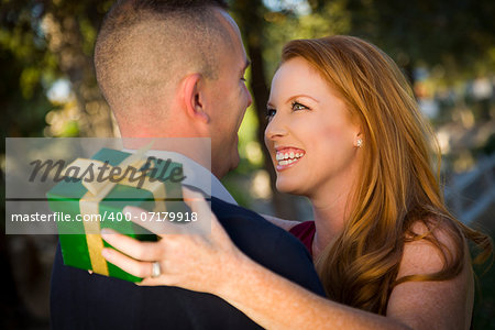 Smiling Beautiful Young Woman and Handsome Military Man Exchange a Christmas Gift.