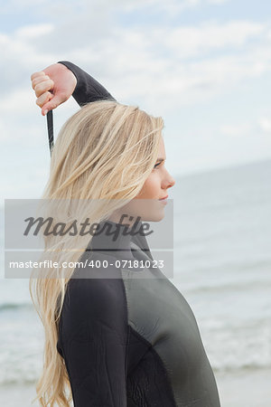 Side view of a young blond in wet suit standing at the beach