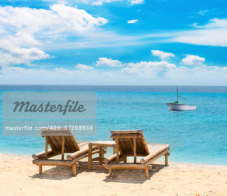 Tropical seascape with small boat bamboo beach beds under blue sky