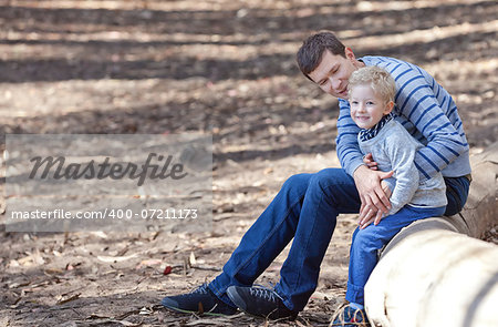 young positive father and his cute smiling son hiking in the woods