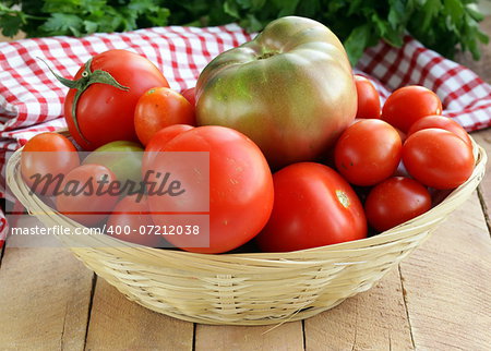 basket with different types of tomatoes on wooden table