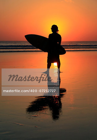 Silhouette of surfer with a board on a sunset