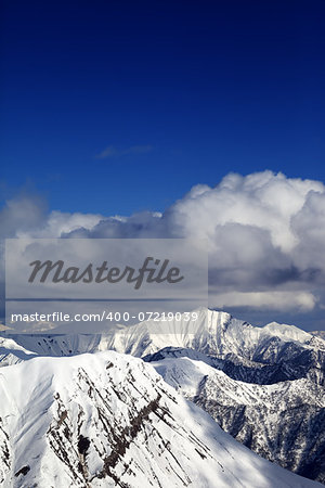 Winter snowy sunlit mountains and sky with clouds. Caucasus Mountains, Georgia, view from ski resort Gudauri.