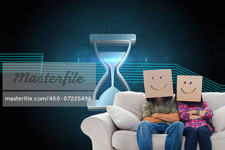 Composite image of silly employees with arms folded wearing boxes on their heads with smiley faces on a couch