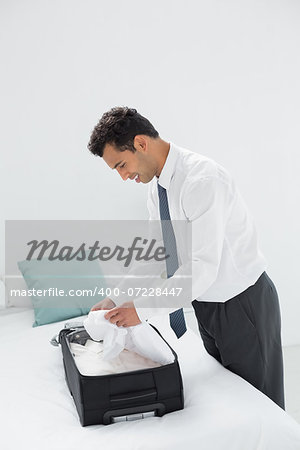 Side view of a businessman unpacking luggage at a hotel bedroom